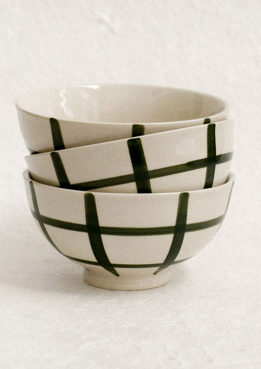 A stack of small white porcelain bowls with painted grid pattern.