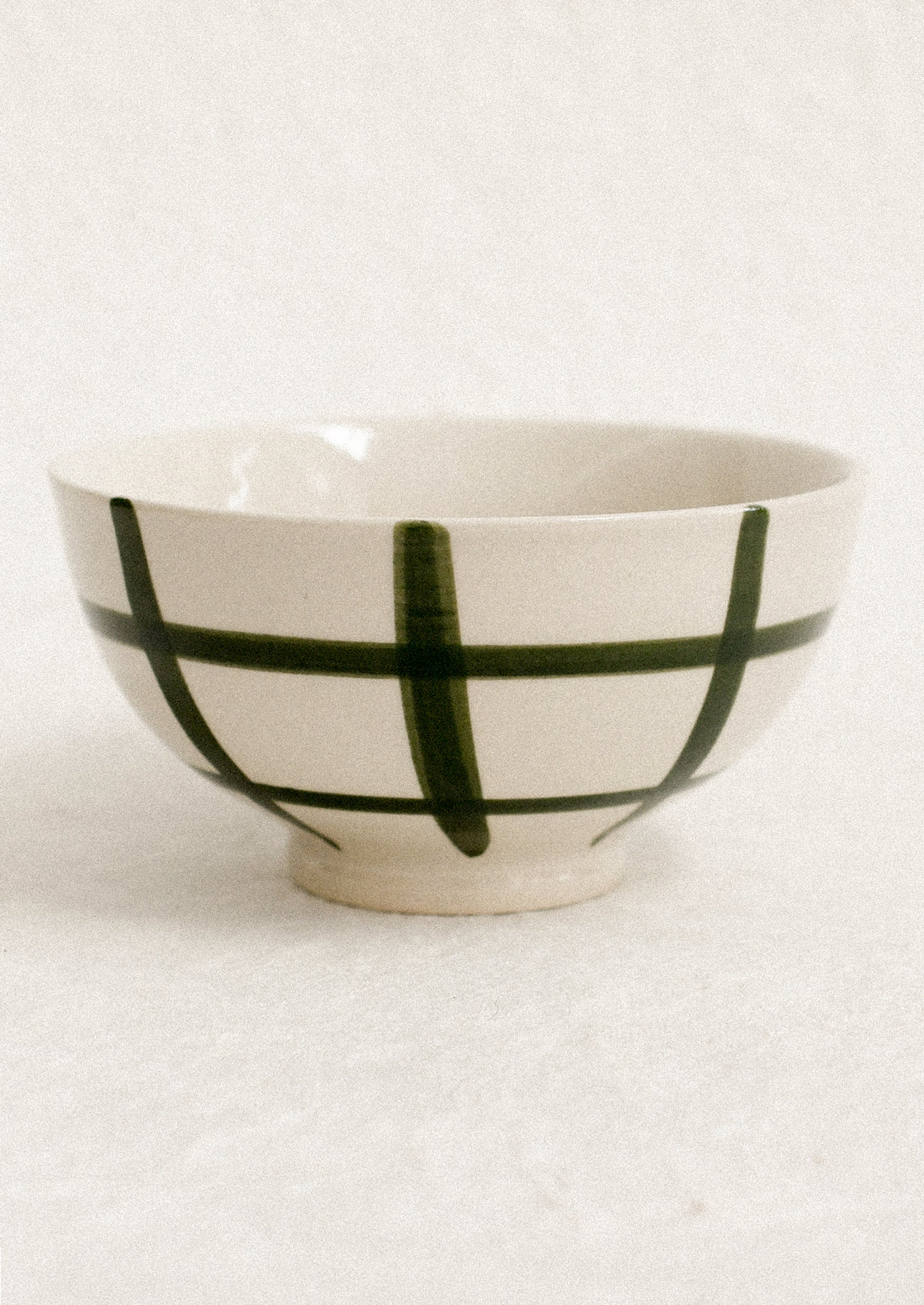 A small white porcelain bowl with painted grid pattern.