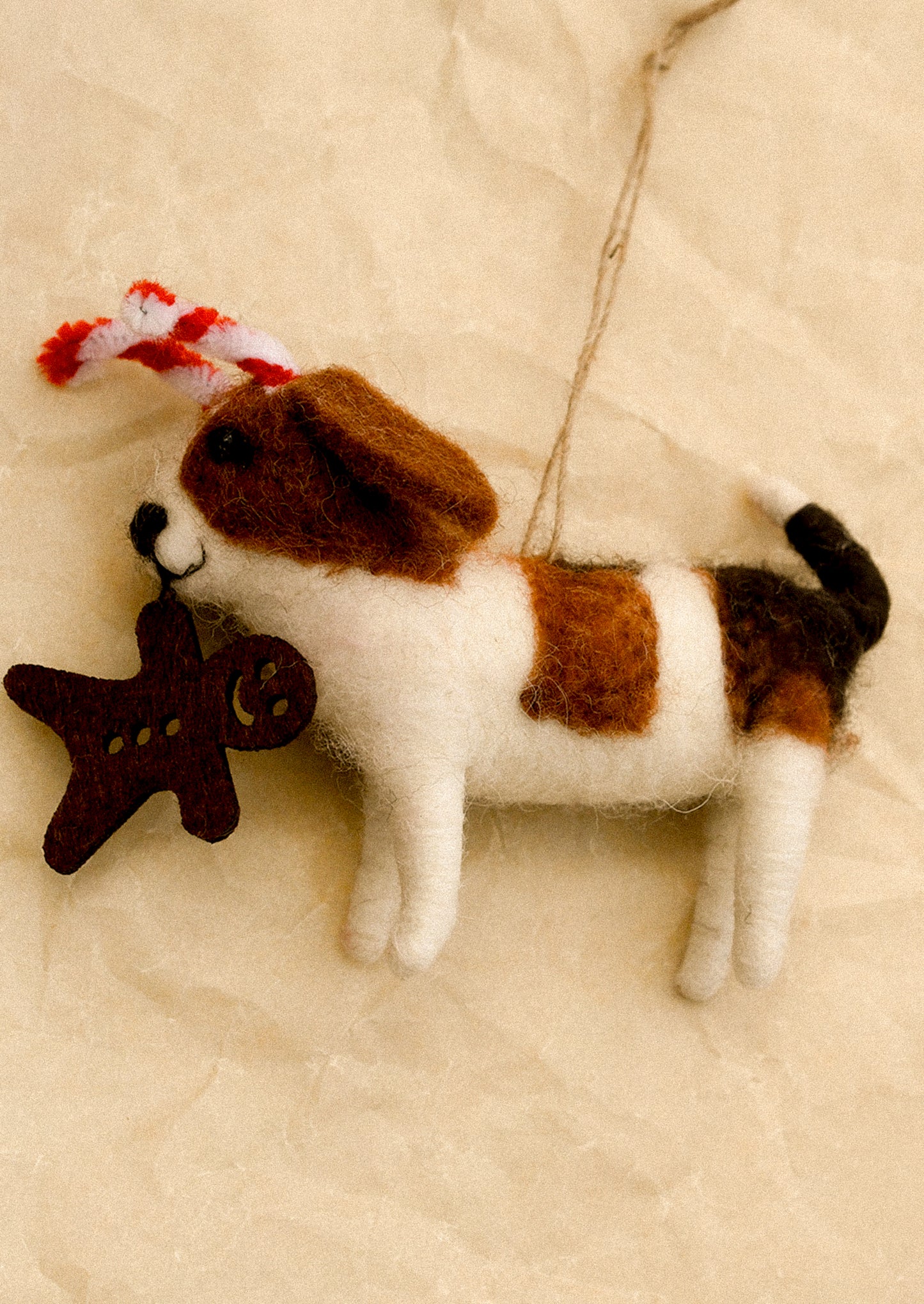 Felted dog ornament with candy cane ears and gingerbread cookie in mouth.
