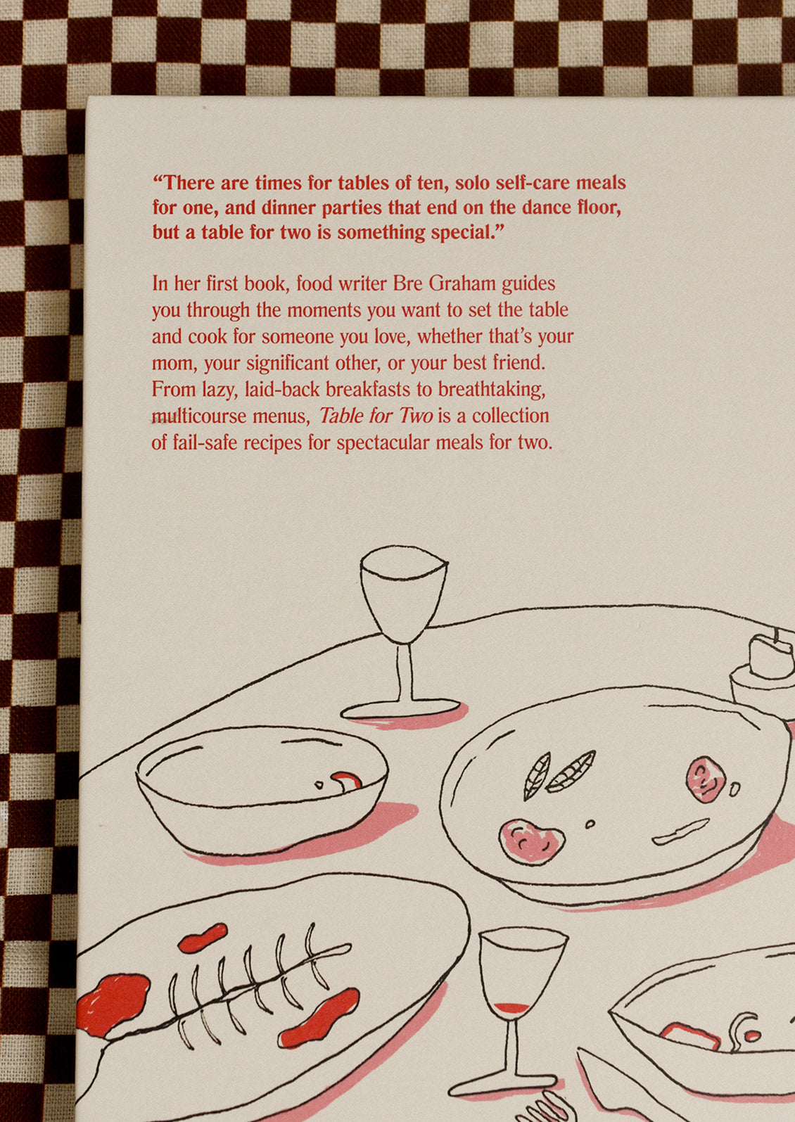 Book cover with text and illustration of a dinner table on a checkered background