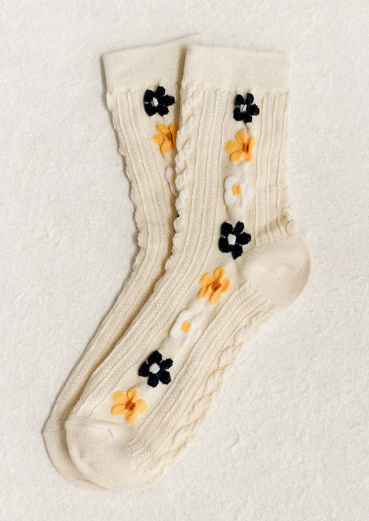 A pair of cream socks with yellow, navy and white floral pattern.