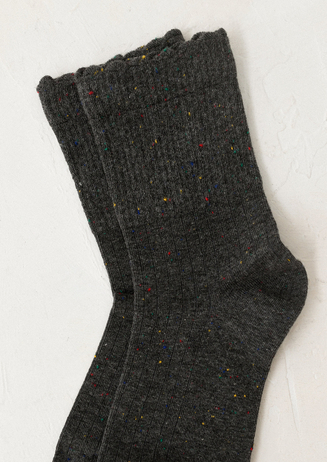 Pair of dark gray socks with speckled pattern on a light background