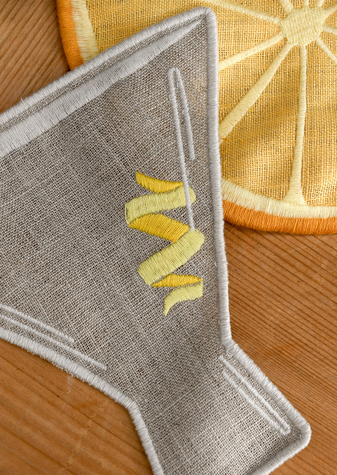 Set of decorative cocktail napkins shaped like an olive, lemon, and martini glass on a wooden surface.