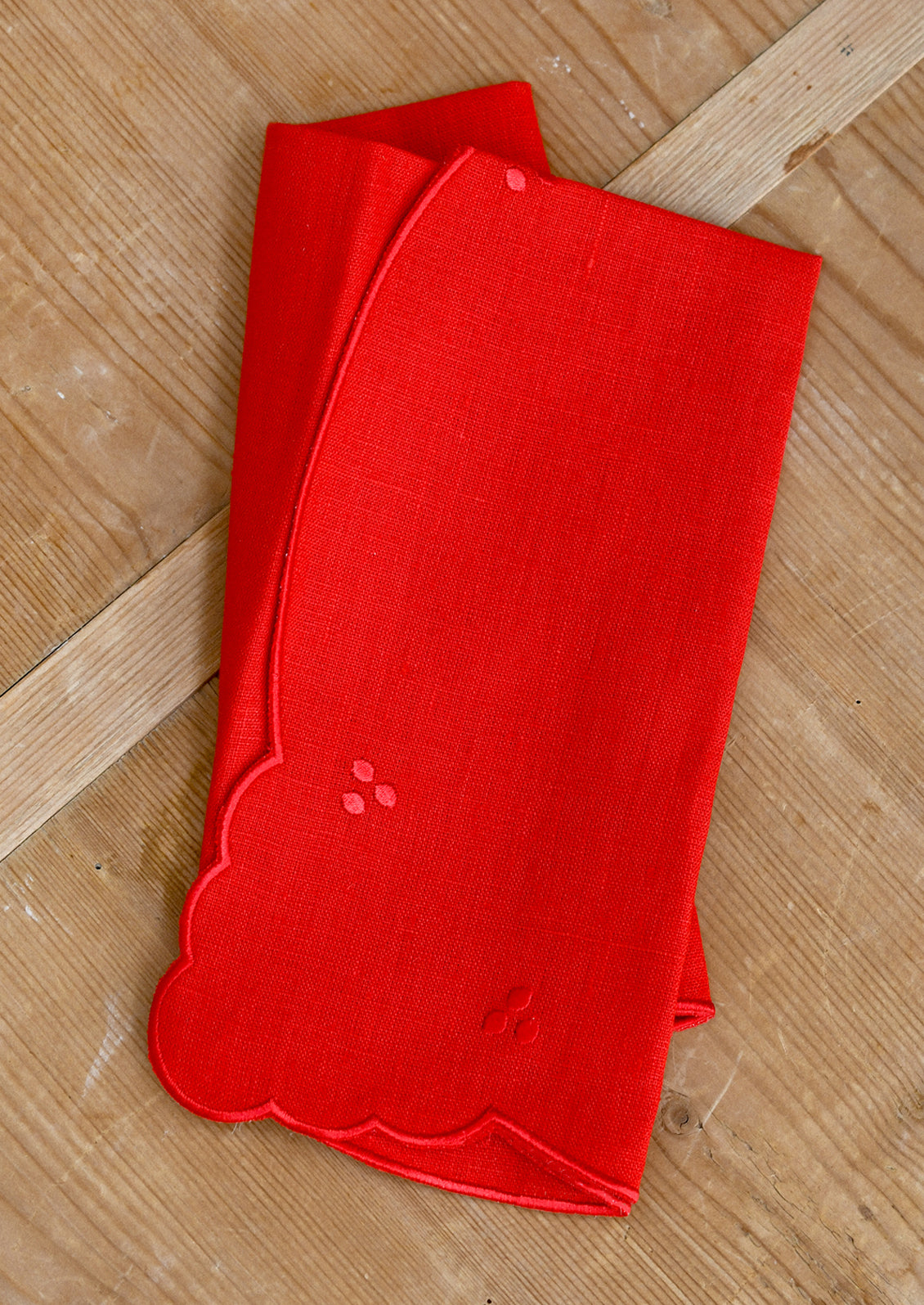 A bright red linen napkin with scalloped embroidery details.