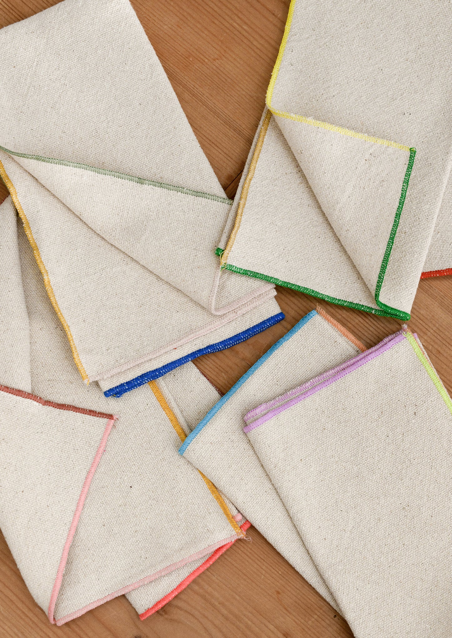 Folded cotton napkins with colorful edges on a wooden surface