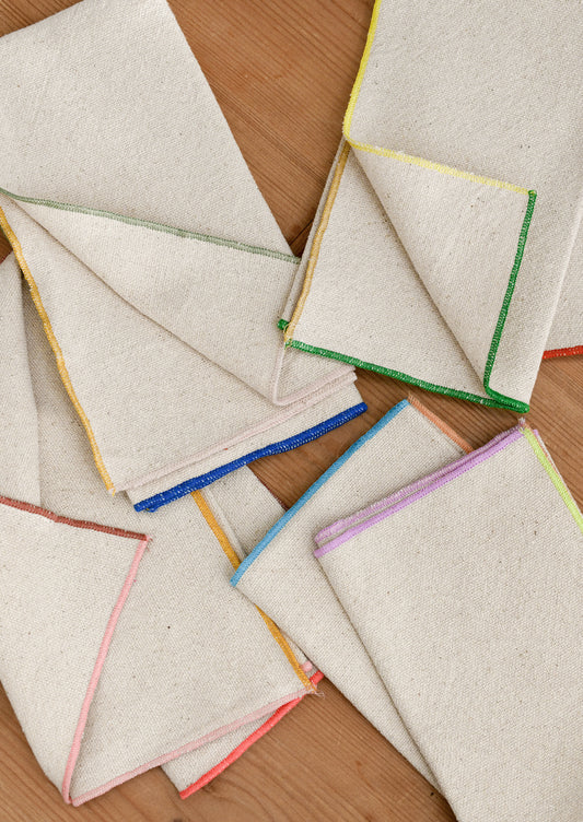 Folded cotton napkins with colorful edges on a wooden surface