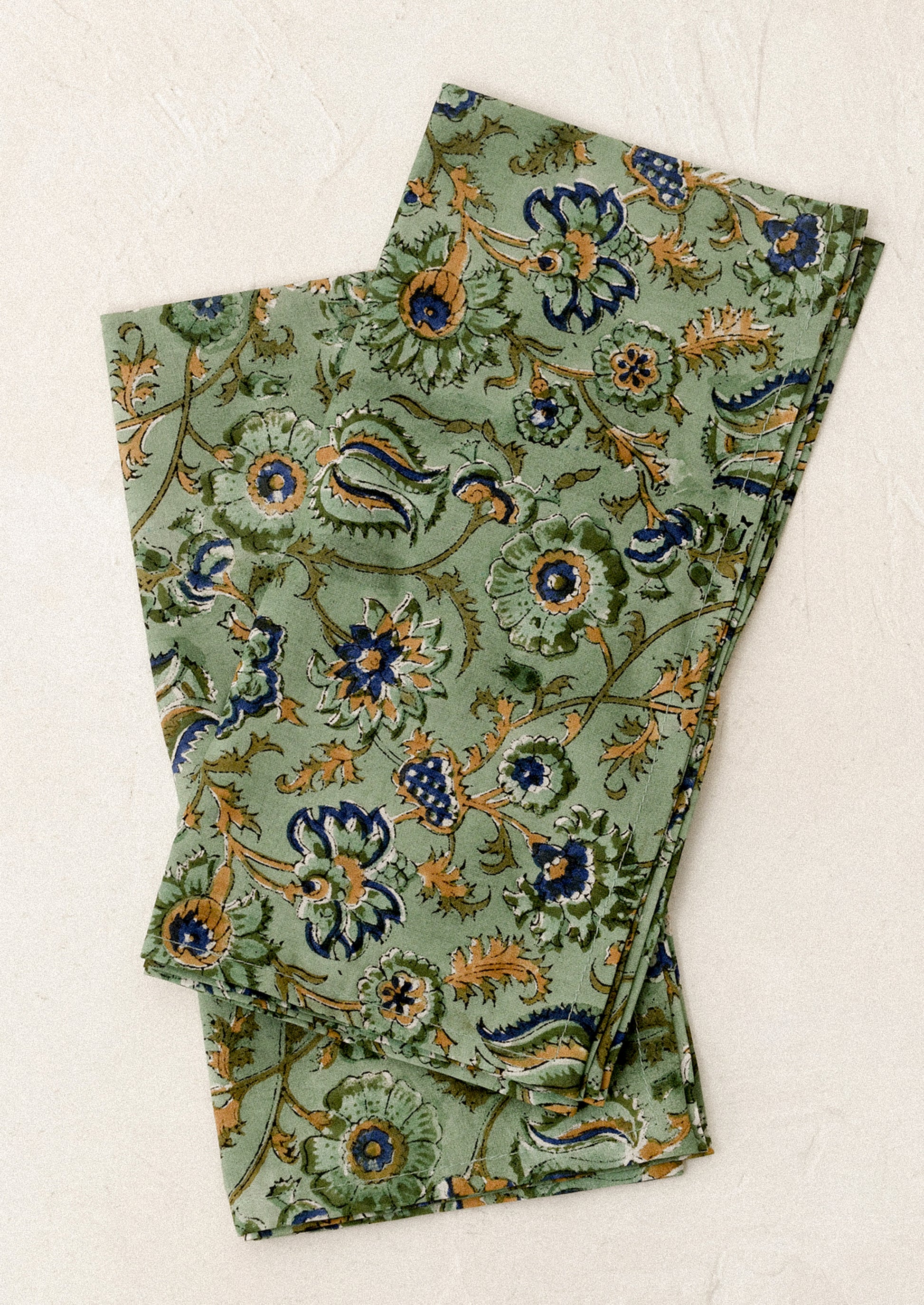 Folded green napkins with floral pattern on a white background
