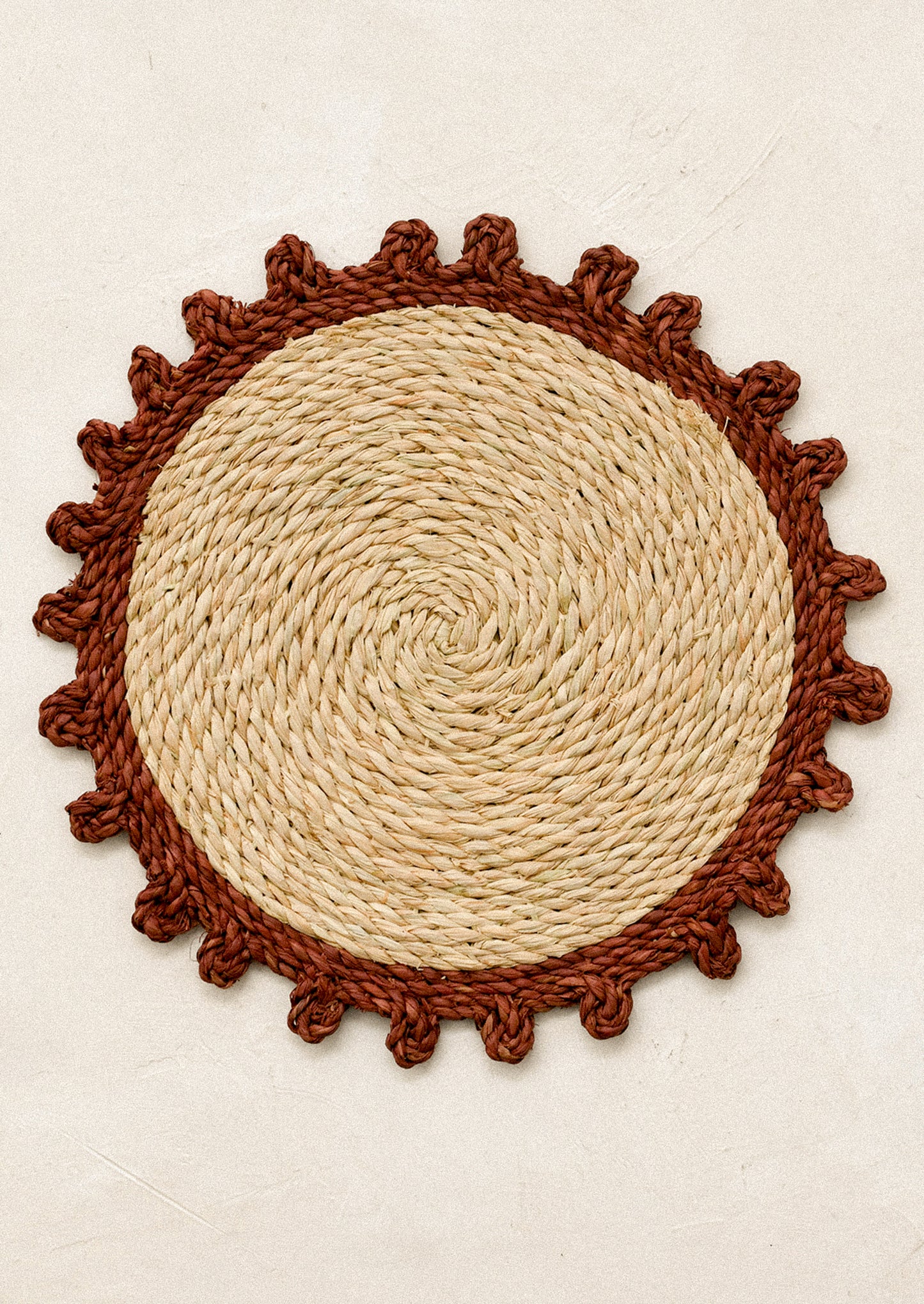 Round woven mat with rust contrast edge.