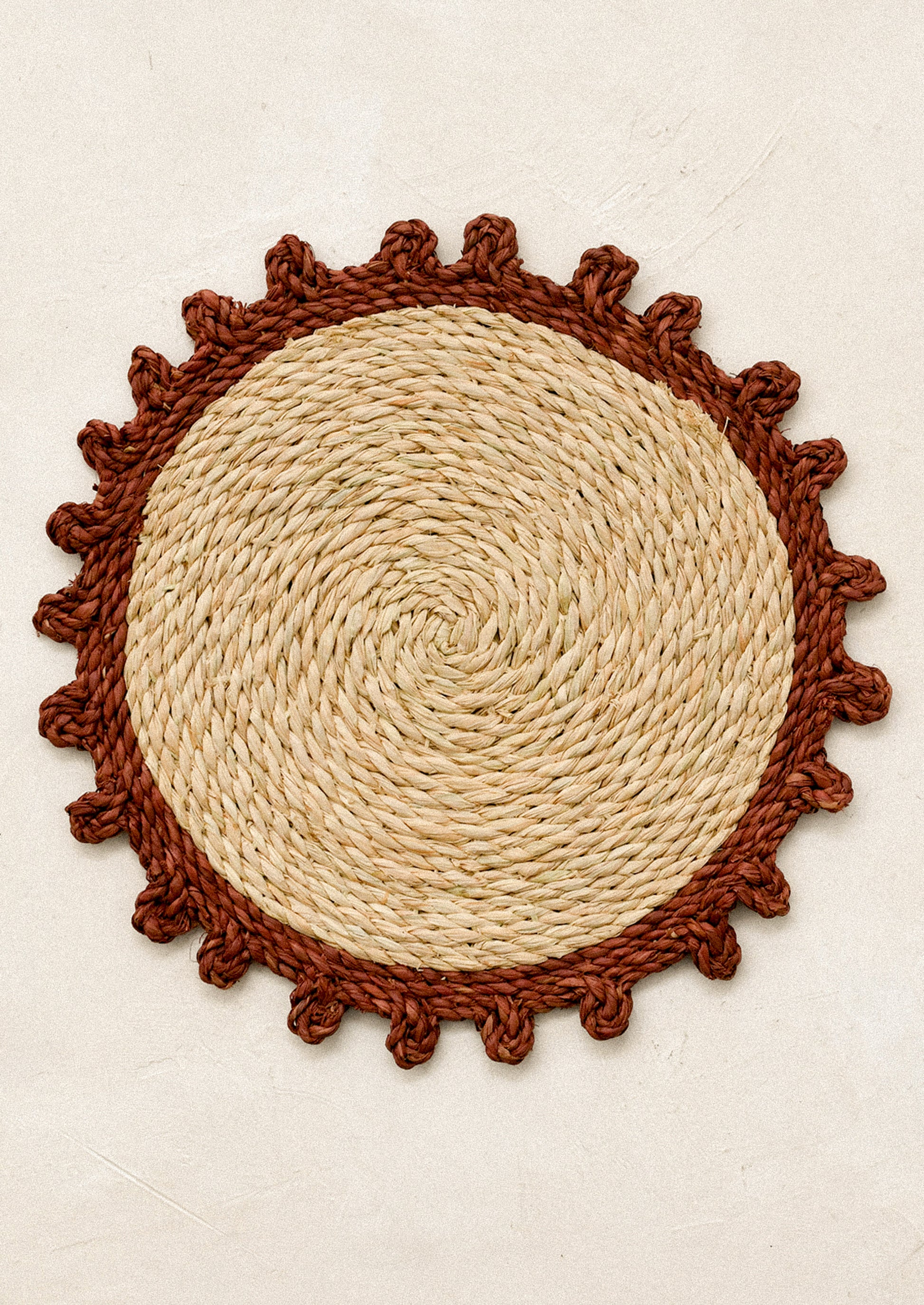Round woven mat with rust contrast edge.