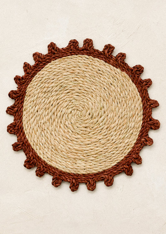 Round woven mat with rust contrast edge.