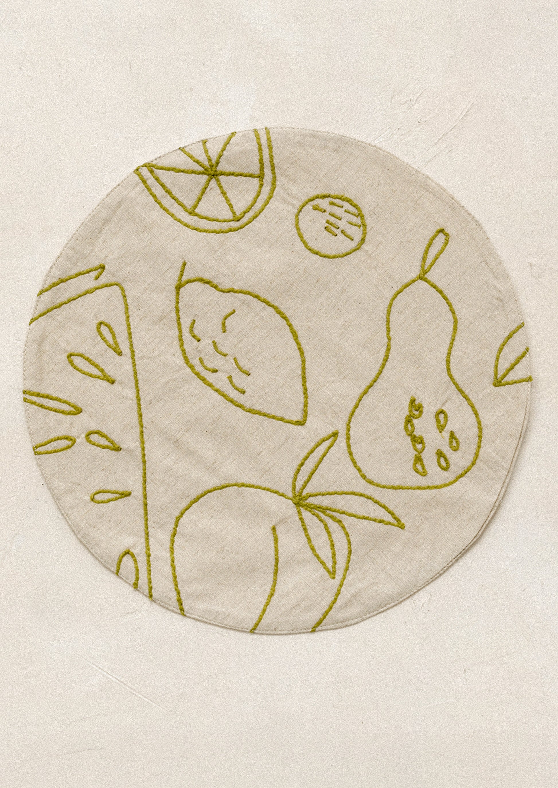Round placemat with embroidered fruit design in green.