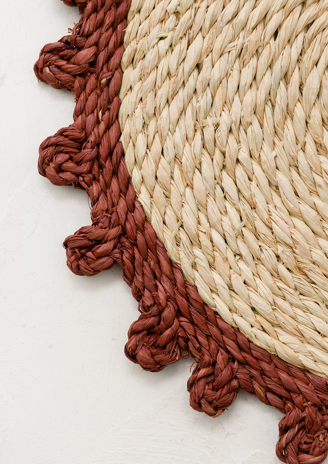 Round woven mat with rust contrast edge.