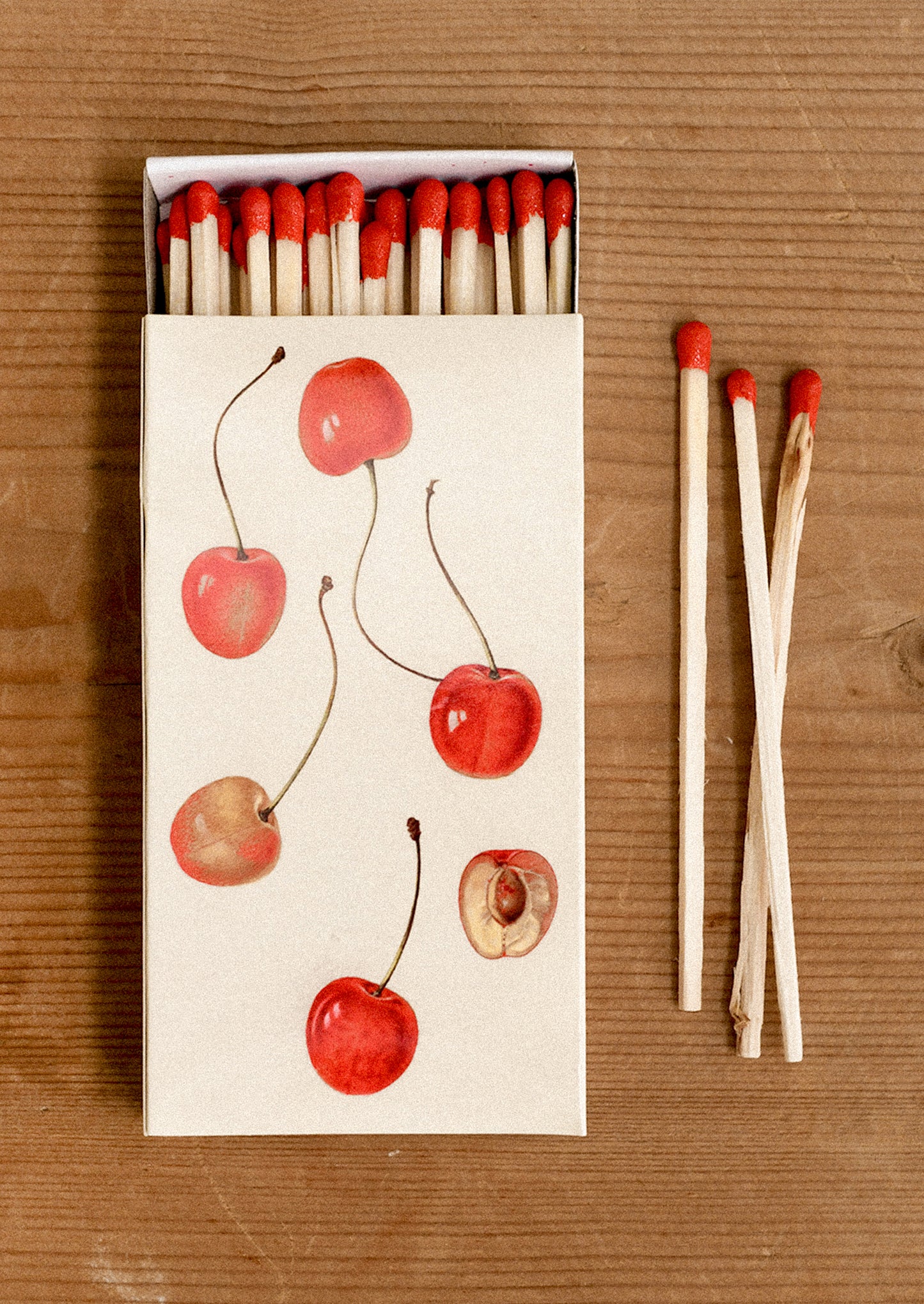 Matchbox with cherry design on a wooden surface