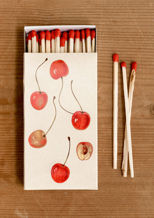 Matchbox with cherry design on a wooden surface