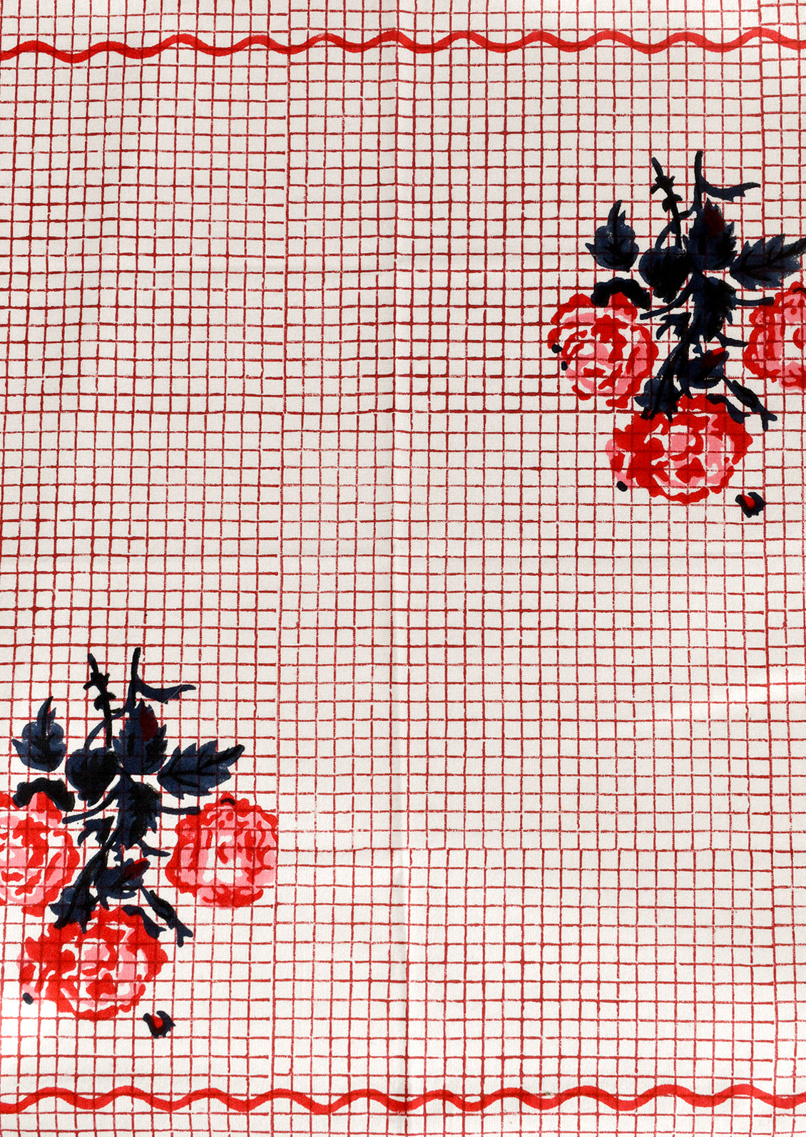 Red grid patterned cloth napkin with floral design and squiggle border.