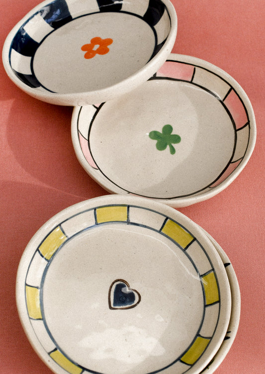 Three ceramic bowls with decorative elements on a pink background
