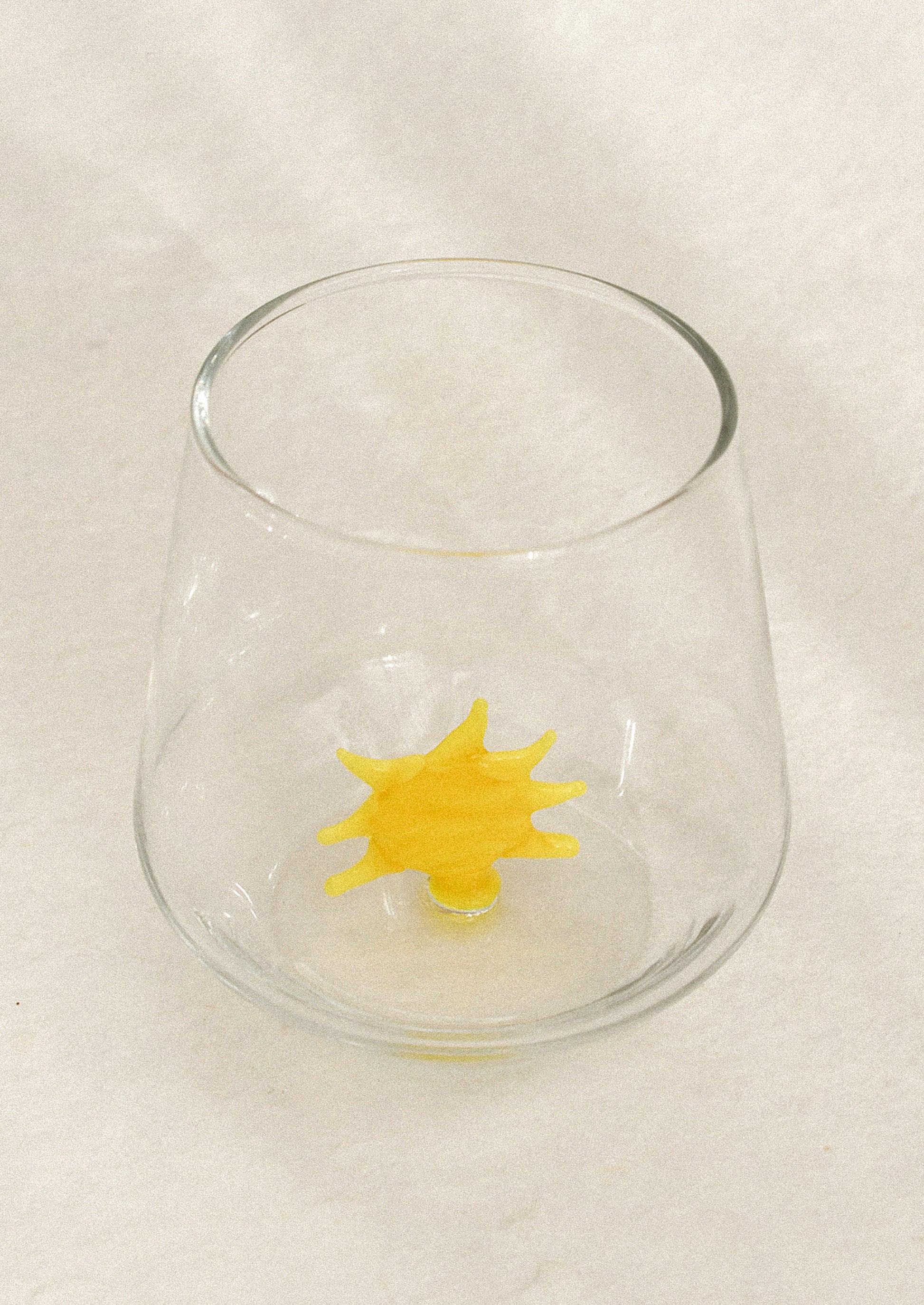Clear glass with a yellow sun-shaped object on the inside.