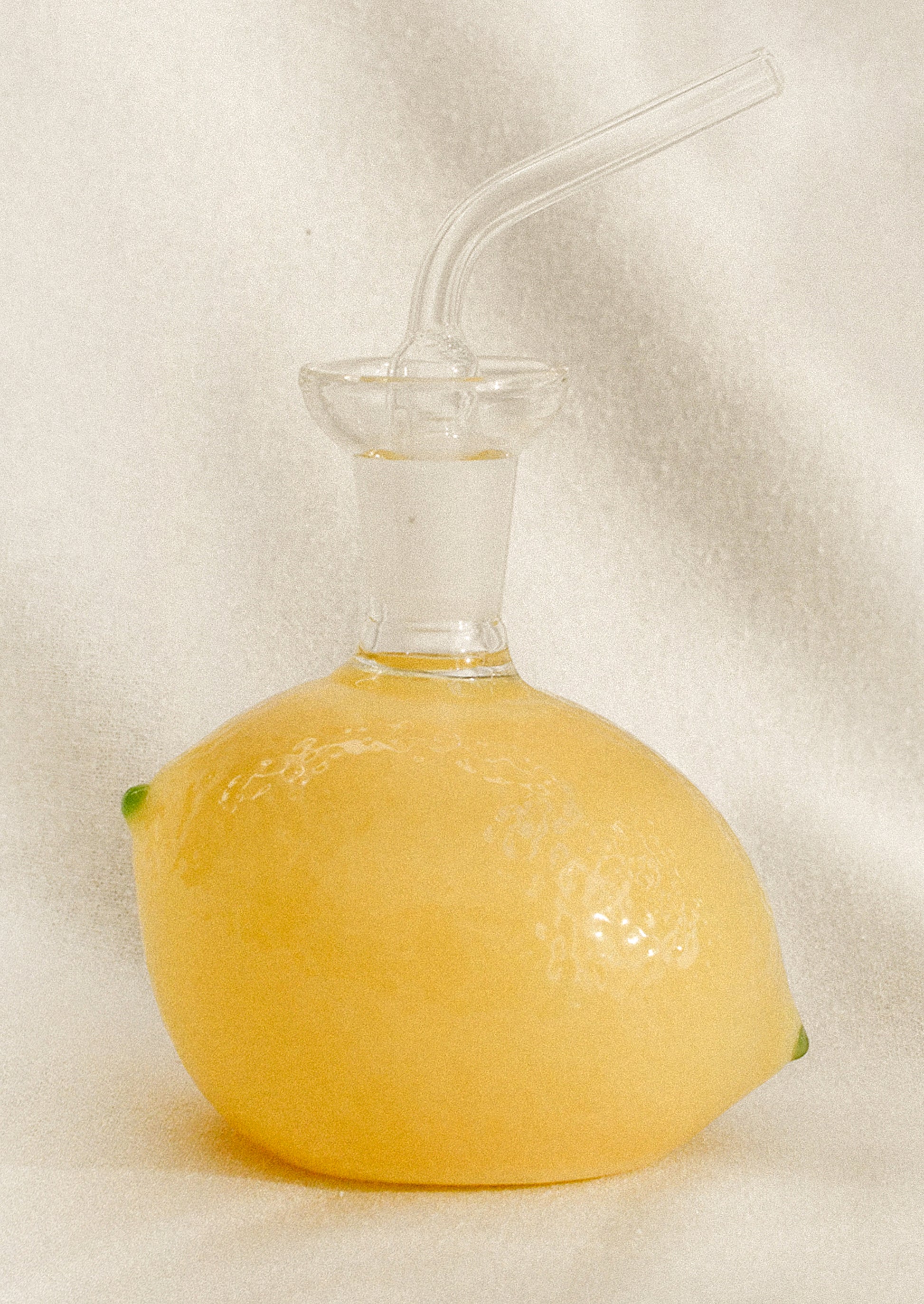 A small glass cruet bottle shaped like a lemon, in yellow with green tips.