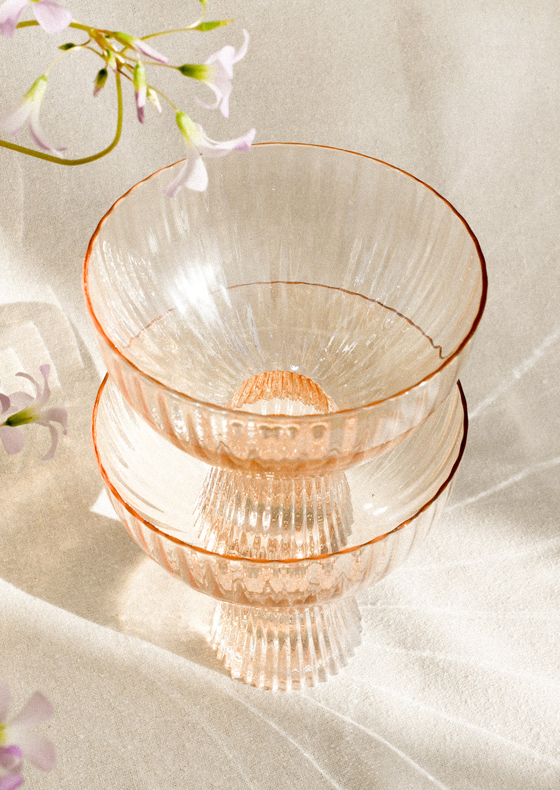 A coupe glass with fluted texture in peach color with iridescent finish.