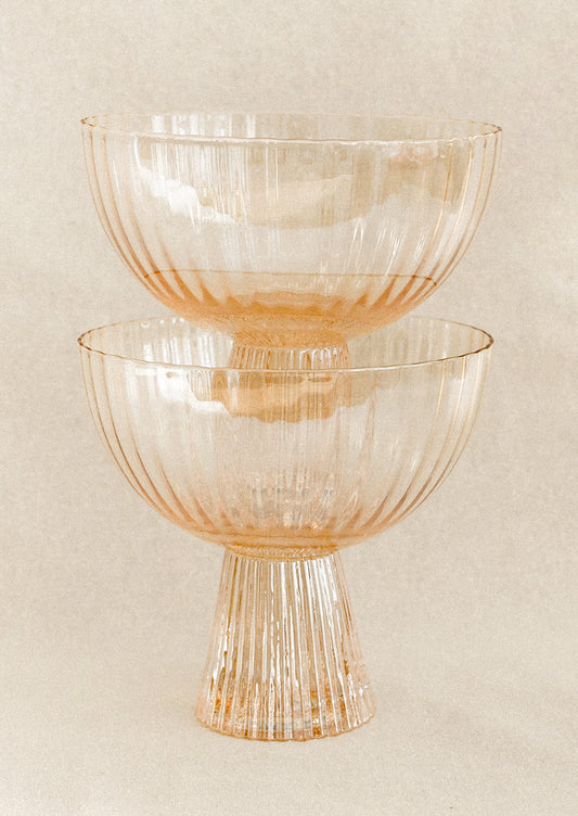 A coupe glass with fluted texture in peach color with iridescent finish.
