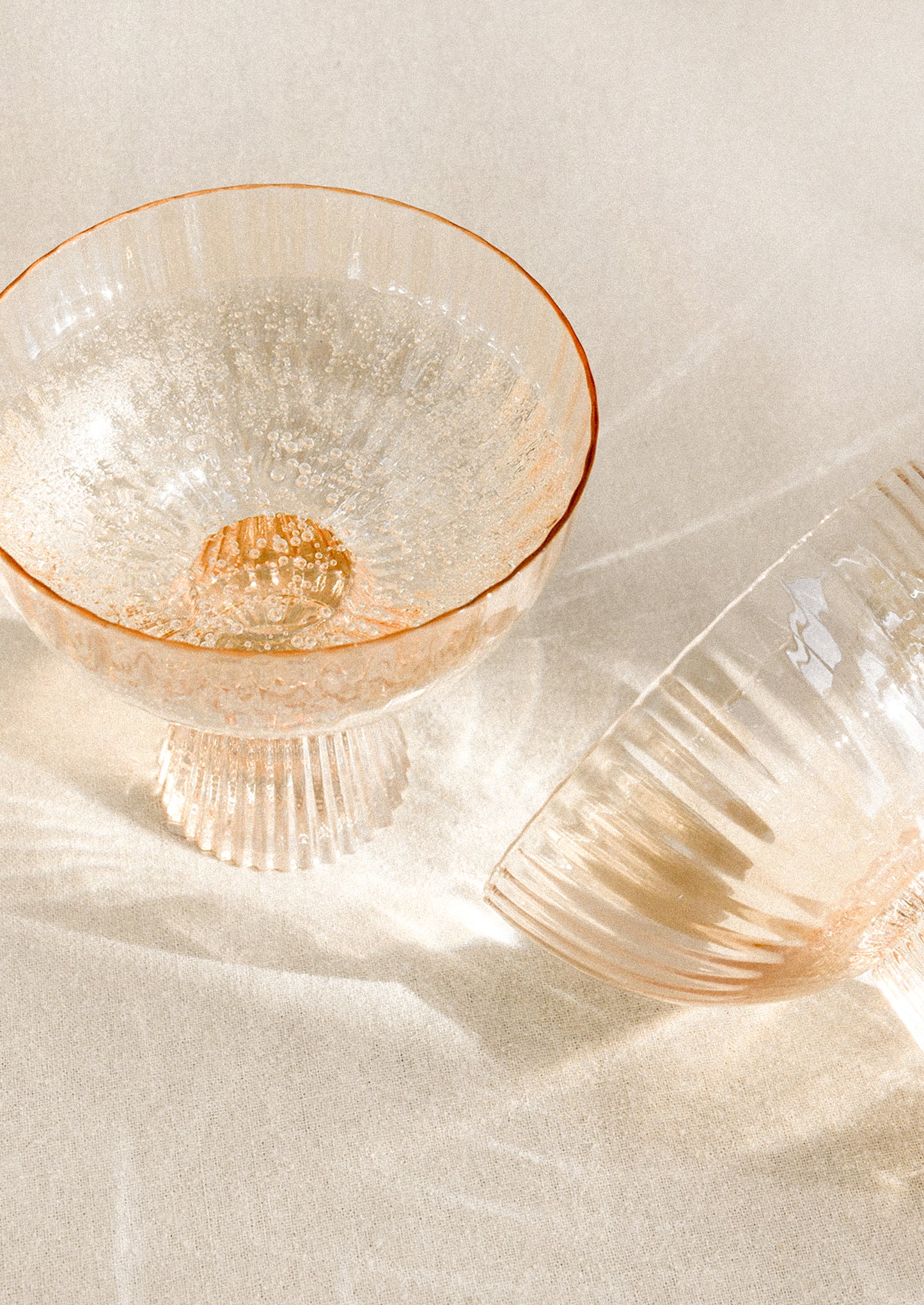 A coupe glass with fluted texture in peach color with iridescent finish.