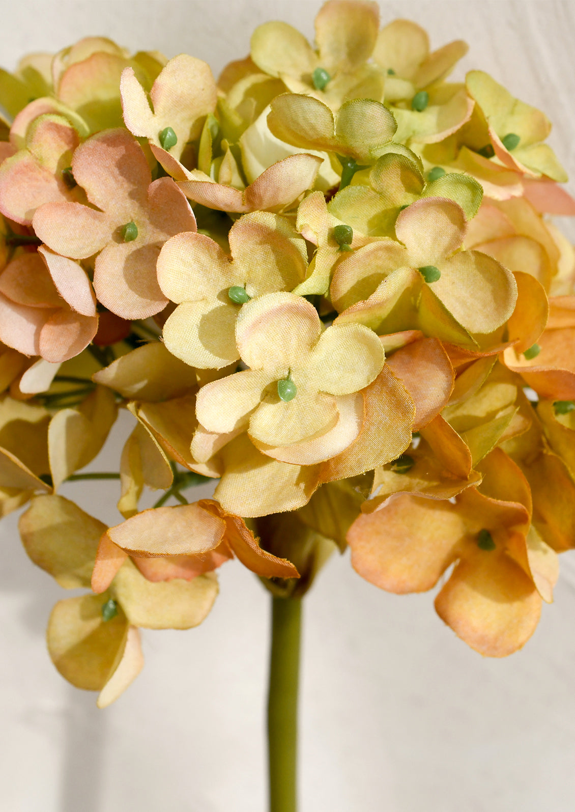 Artificial flower with peach and green flowers on a white background