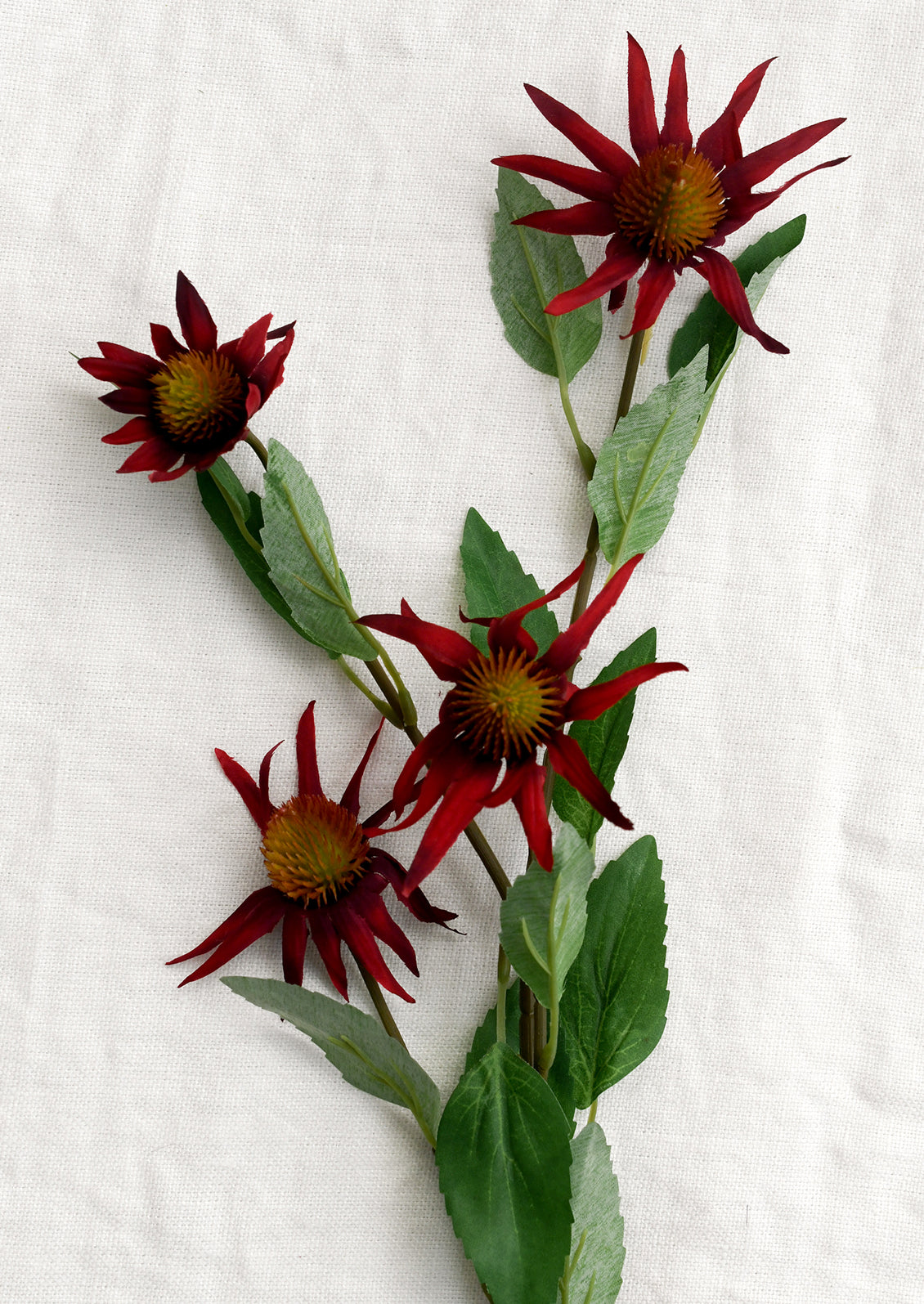 Artificial red flowers with green leaves on a white background