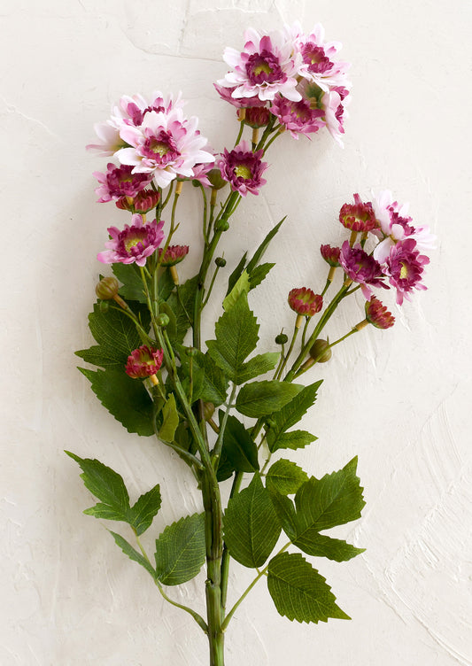 Artificial flower stem with pink and purple flowers on a white background