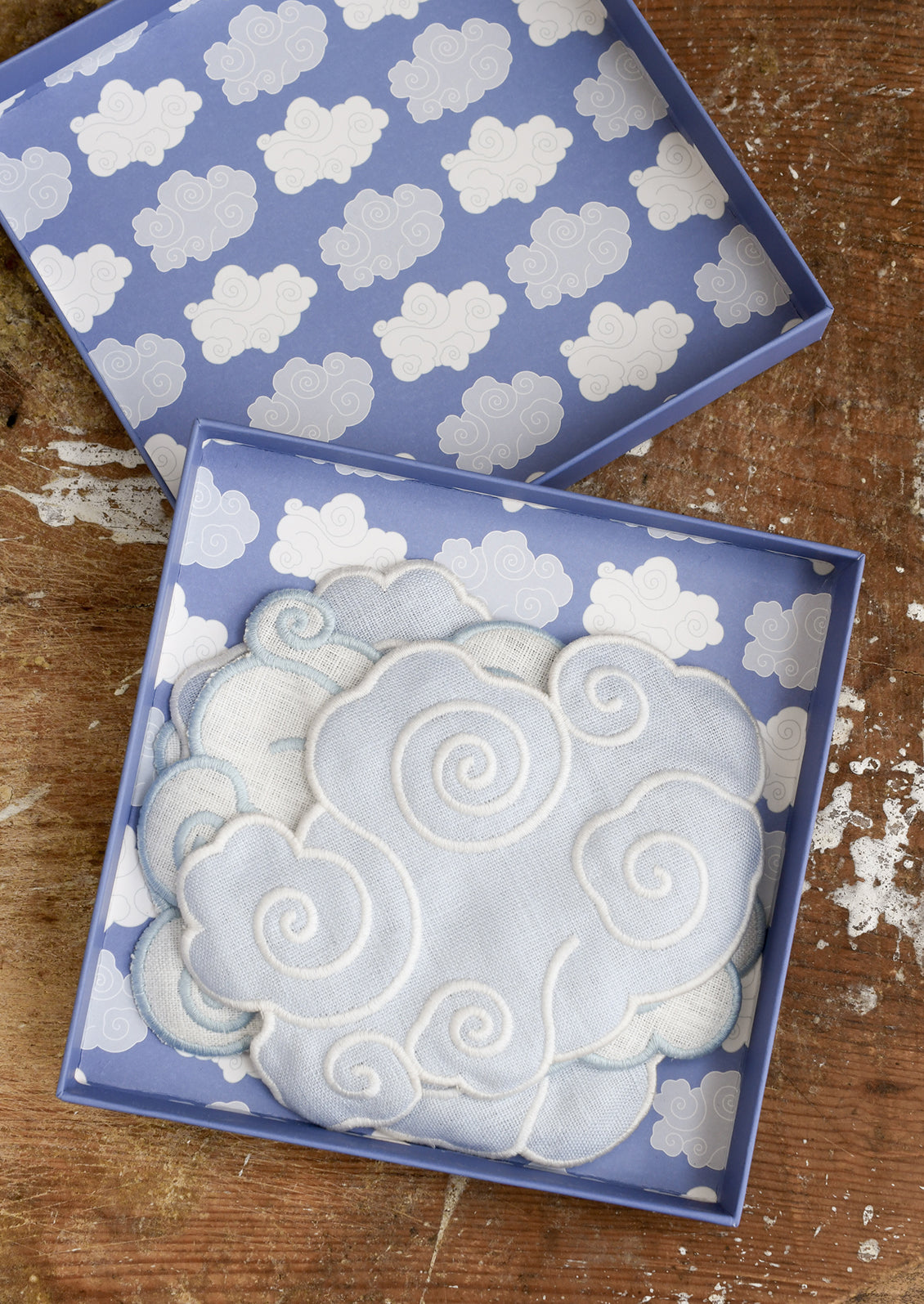 Two decorative boxes with cloud patterns on a wooden surface