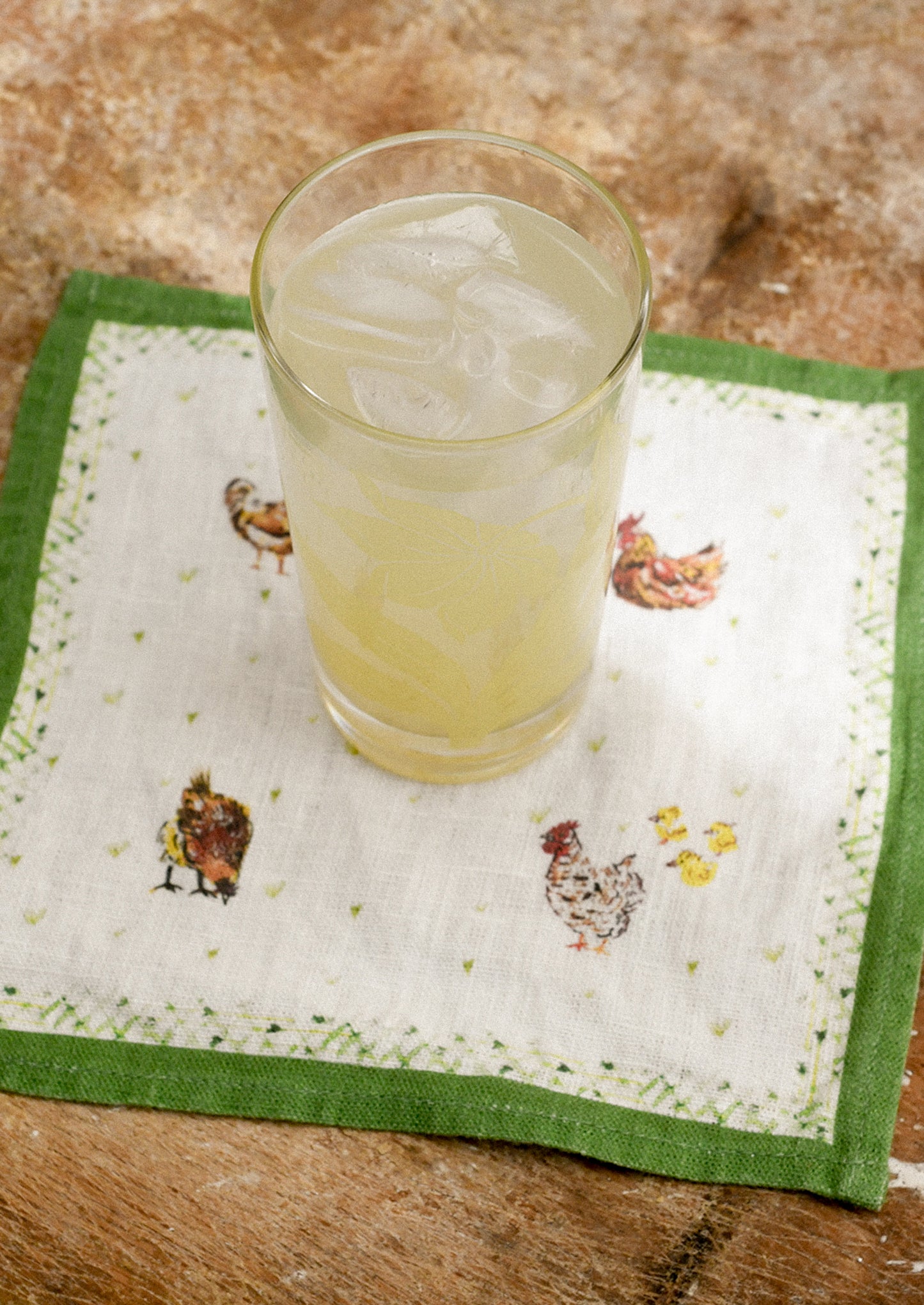 Glass of lemonade with ice on a decorative napkin with animal illustrations.
