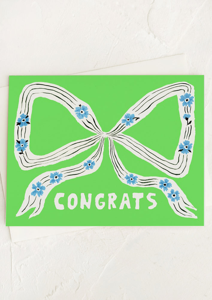 A neon green card with illustration of ribbon bow with floral details, text reads "Congrats".