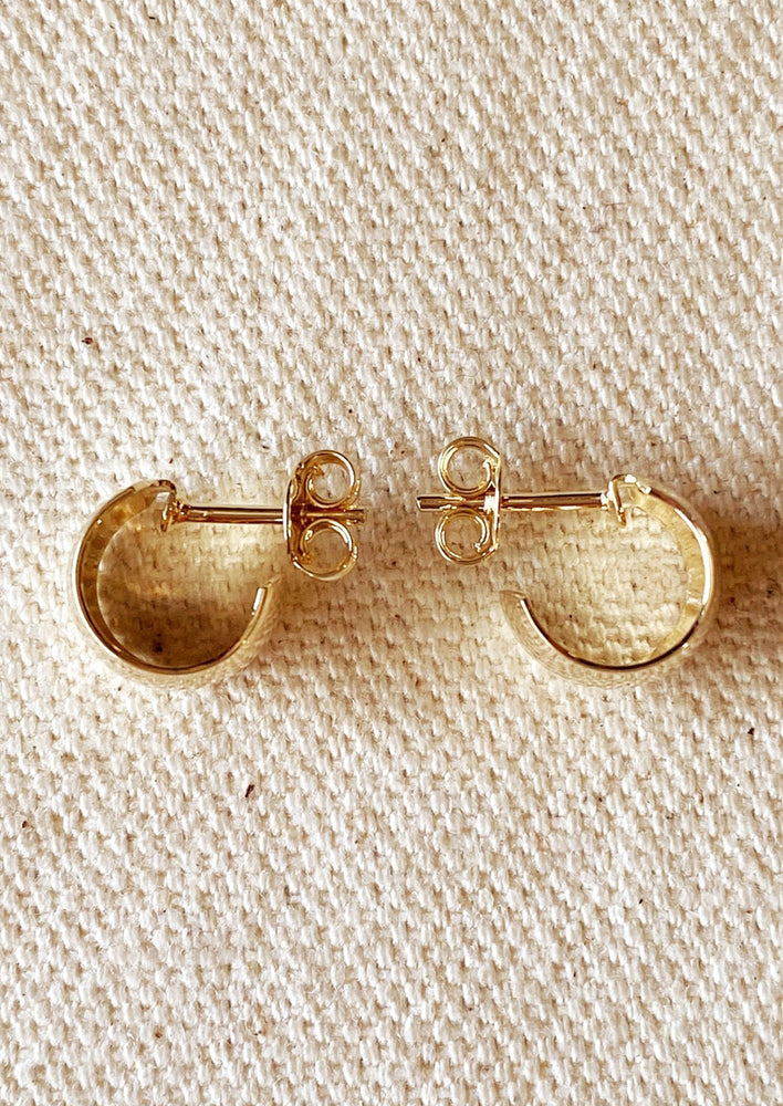 A pair of wide and thick chunky mini hoop earrings with post back in gold.