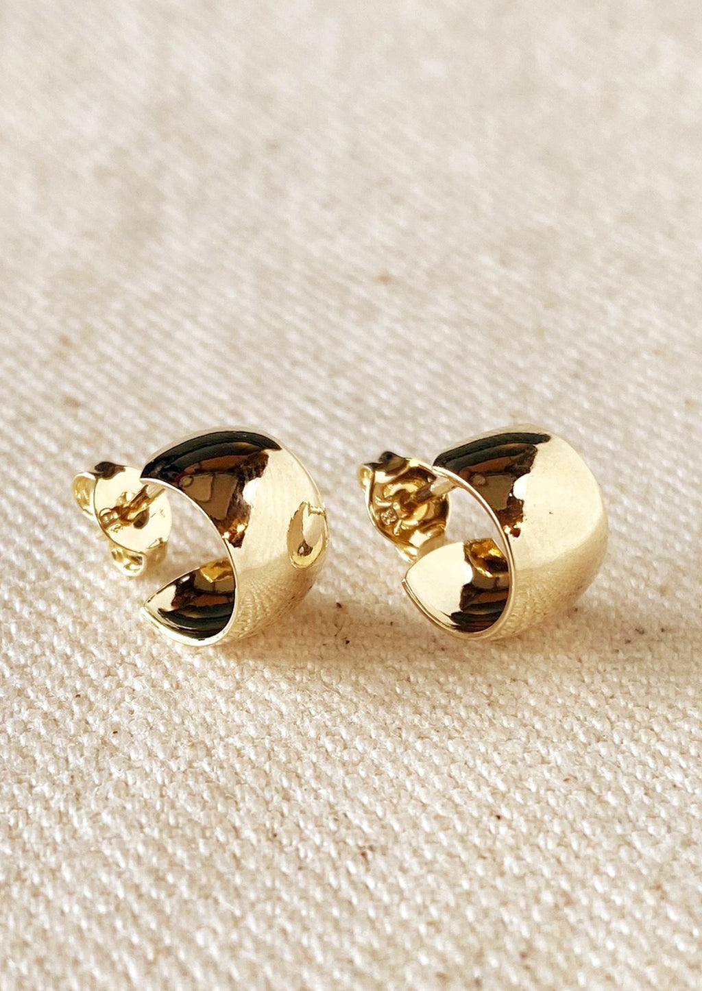 1: A pair of wide and thick chunky mini hoop earrings with post back in gold.