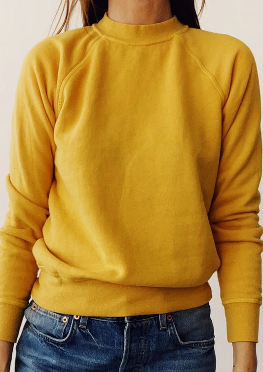 A person wearing a fitted crewneck fleece sweatshirt in goldenrod yellow.