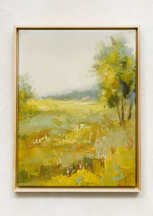 A framed oil landscape painting of a yellow-green meadow.