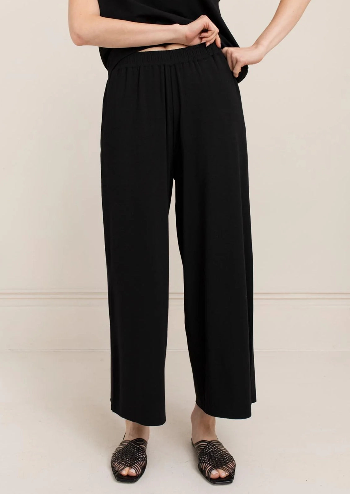 A person wearing a pair of black wide leg pants.