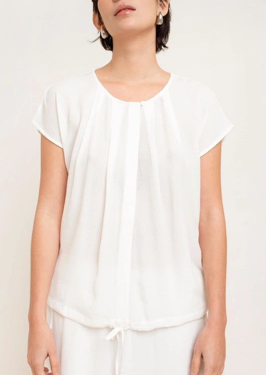 Person wearing a white top and pants on a plain background