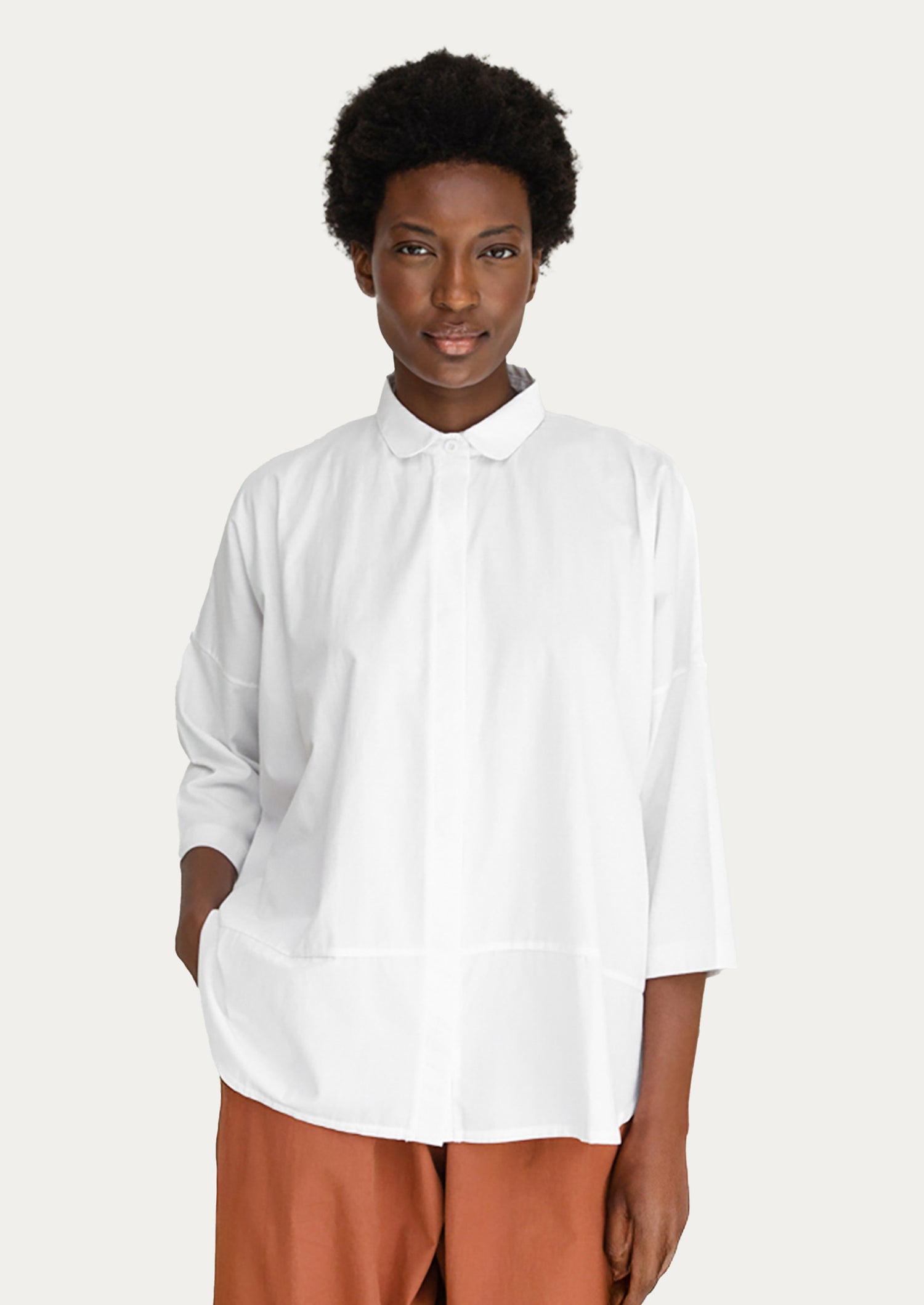 A woman wearing a blousy white cotton shirt.