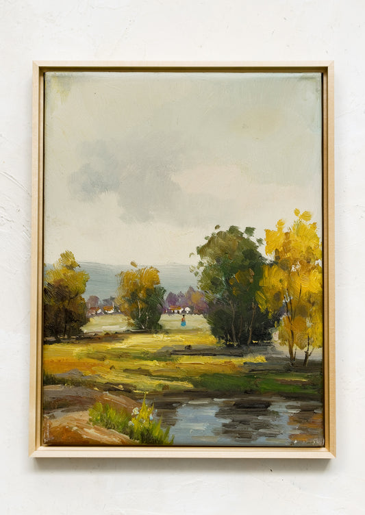 A framed oil landscape painting of trees near a pond.