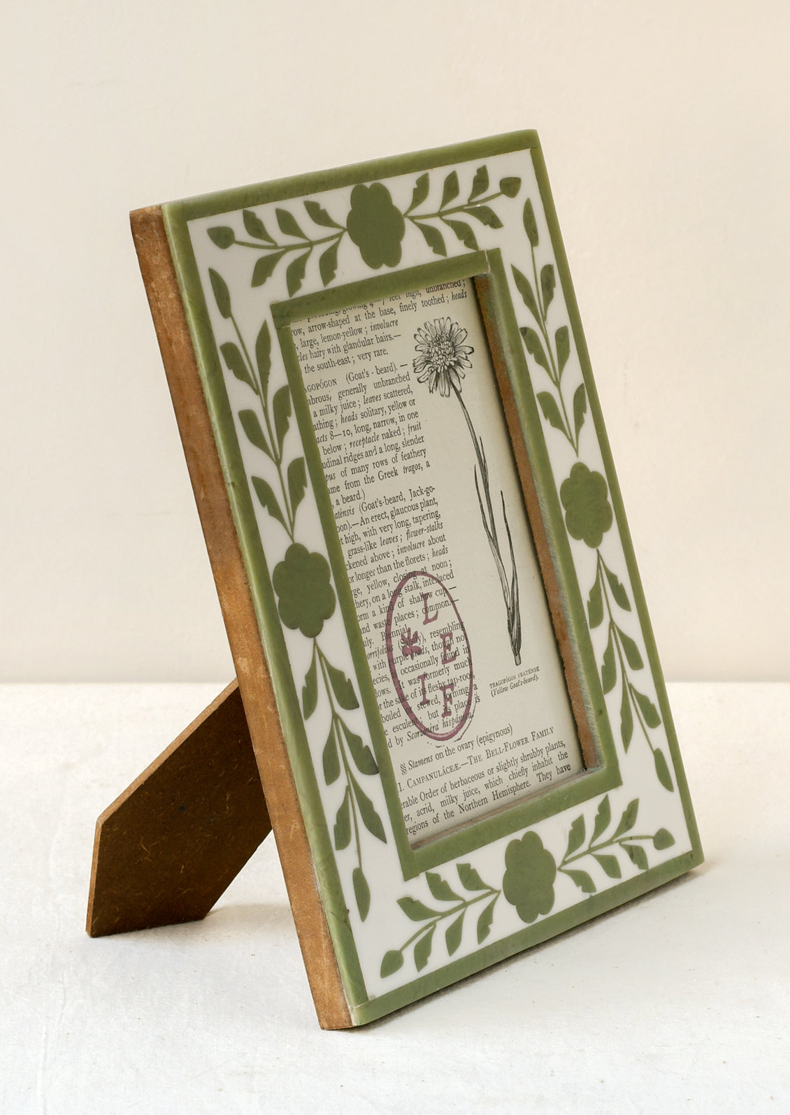 A 4" x 6" picture frame with a green floral design and a wood backing.