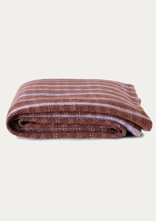 Folded striped blanket with brown and lilac hues.