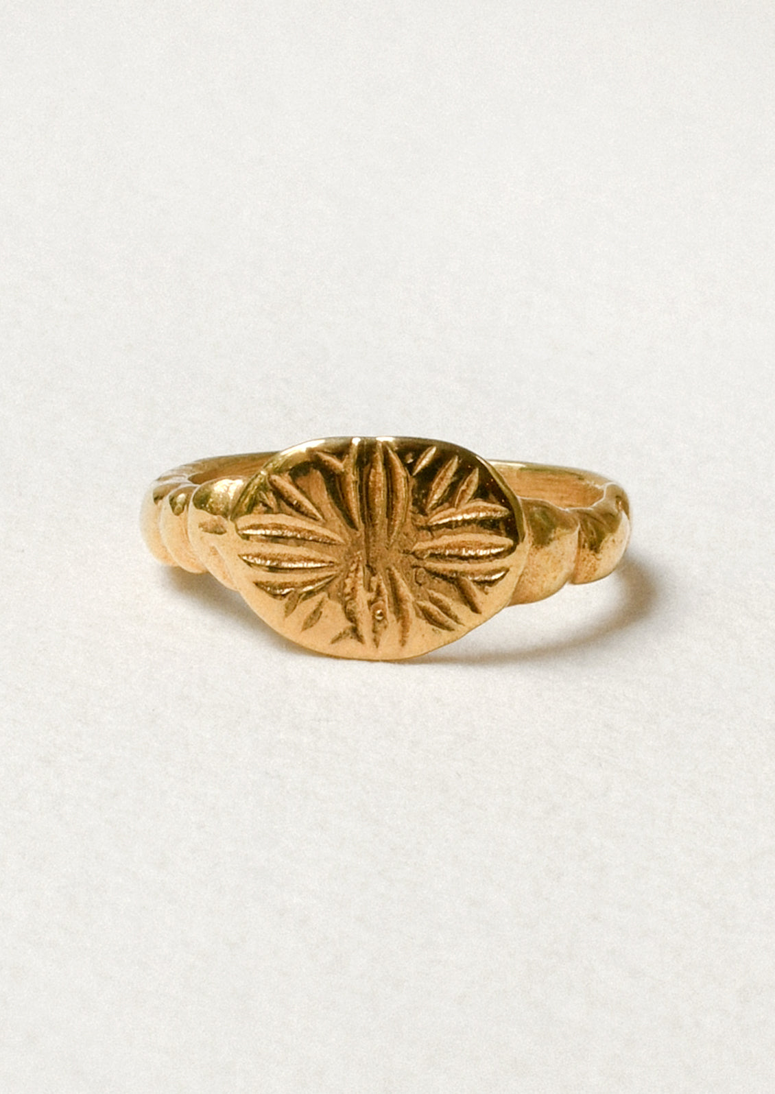 A gold ring with a star-like design engraved on the front.