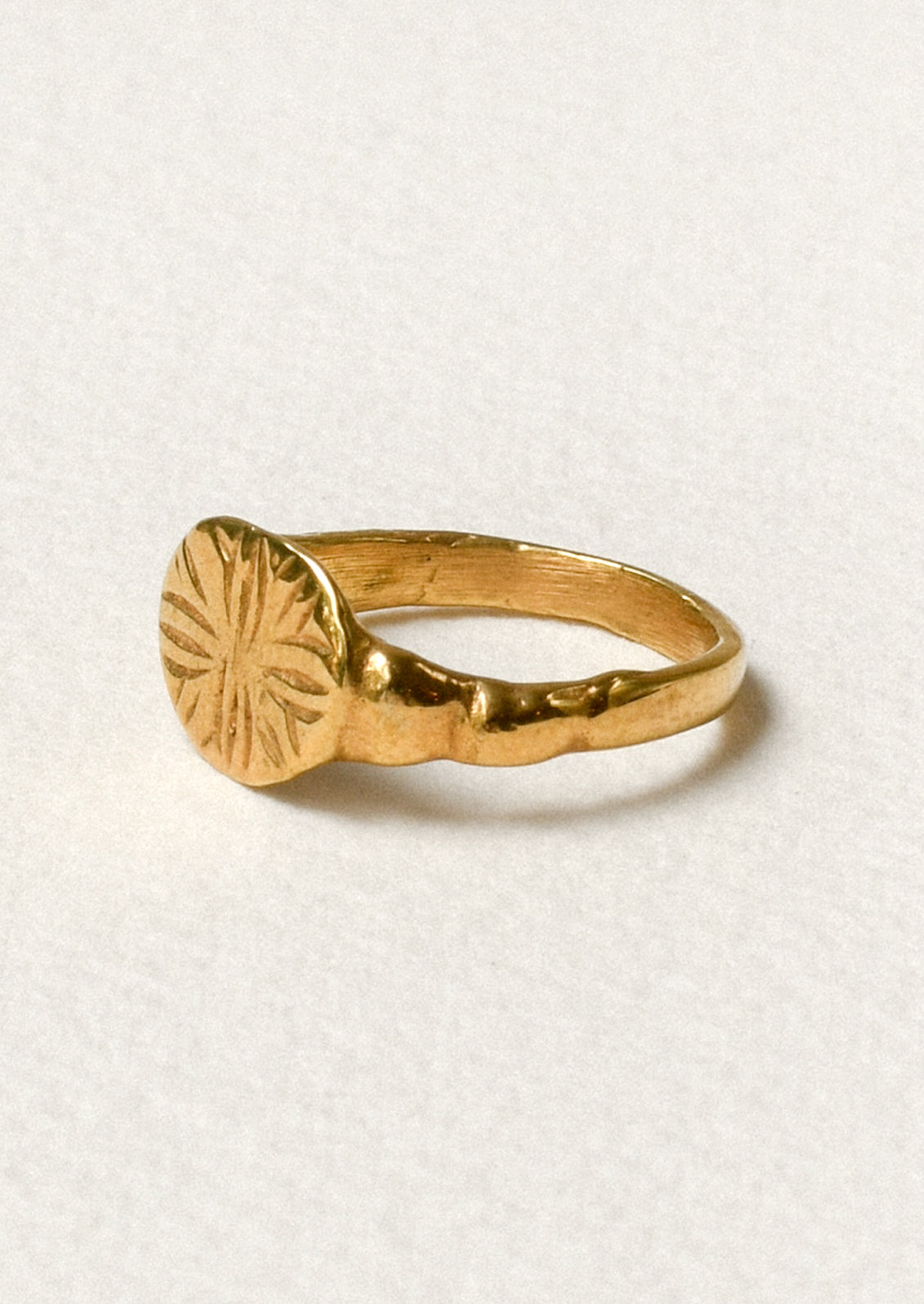 Side view of a gold ring with a star-like design engraved on the front.