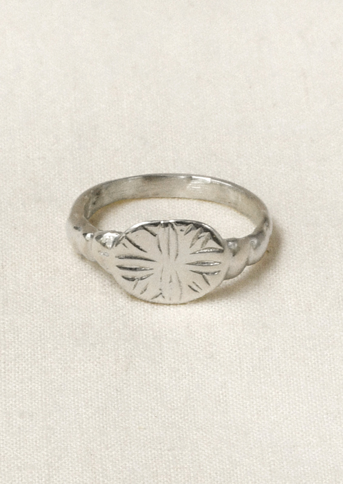 A sterling silver ring with a star-like design engraved on the front.