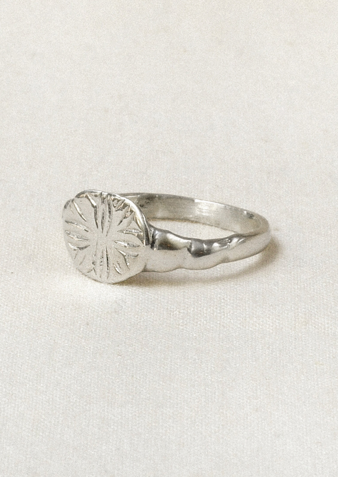 Side view of a sterling silver ring with a star-like design engraved on the front.