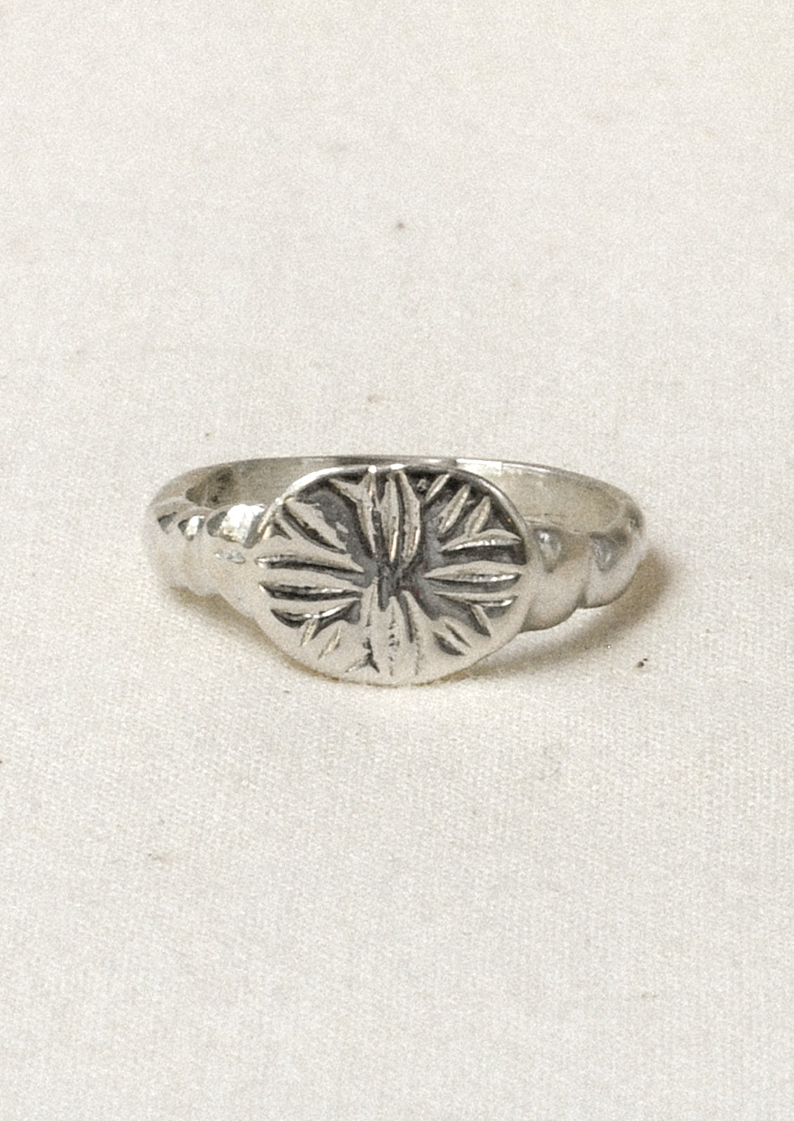 A sterling silver ring with a star-like design engraved on the front.