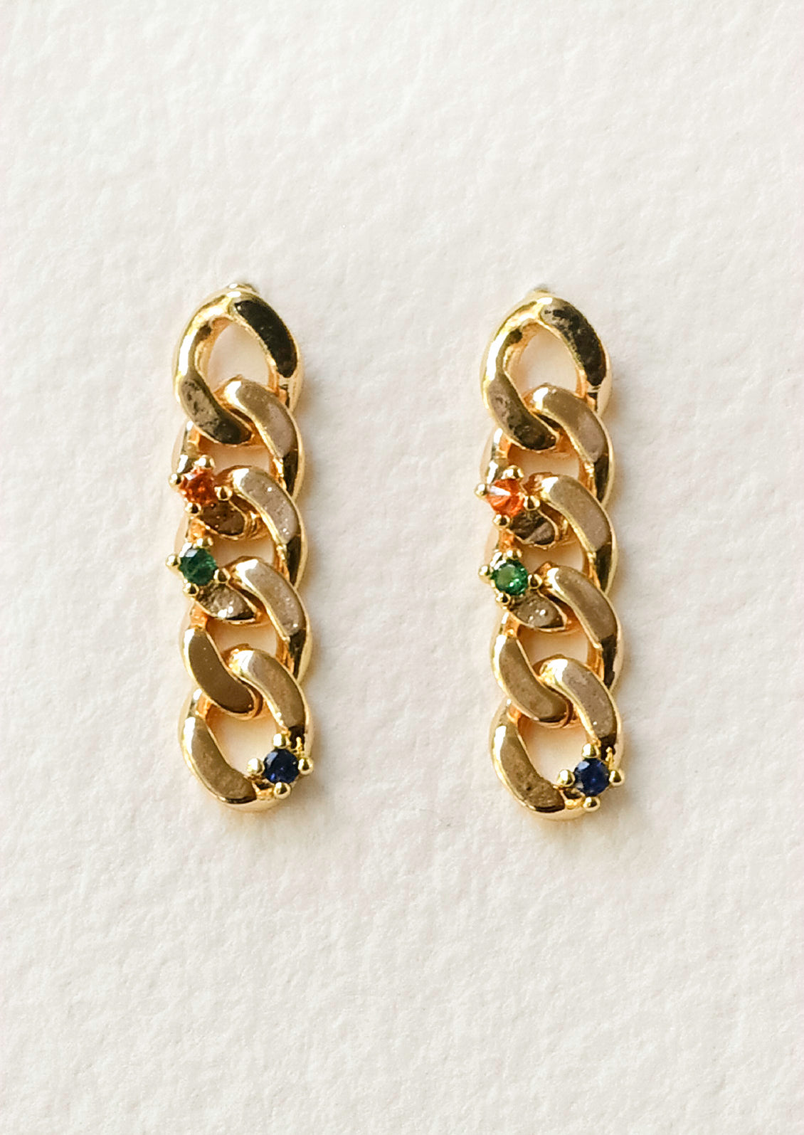 A pair of gold stud earrings with a chainlink design and orange, green, and blue gems.