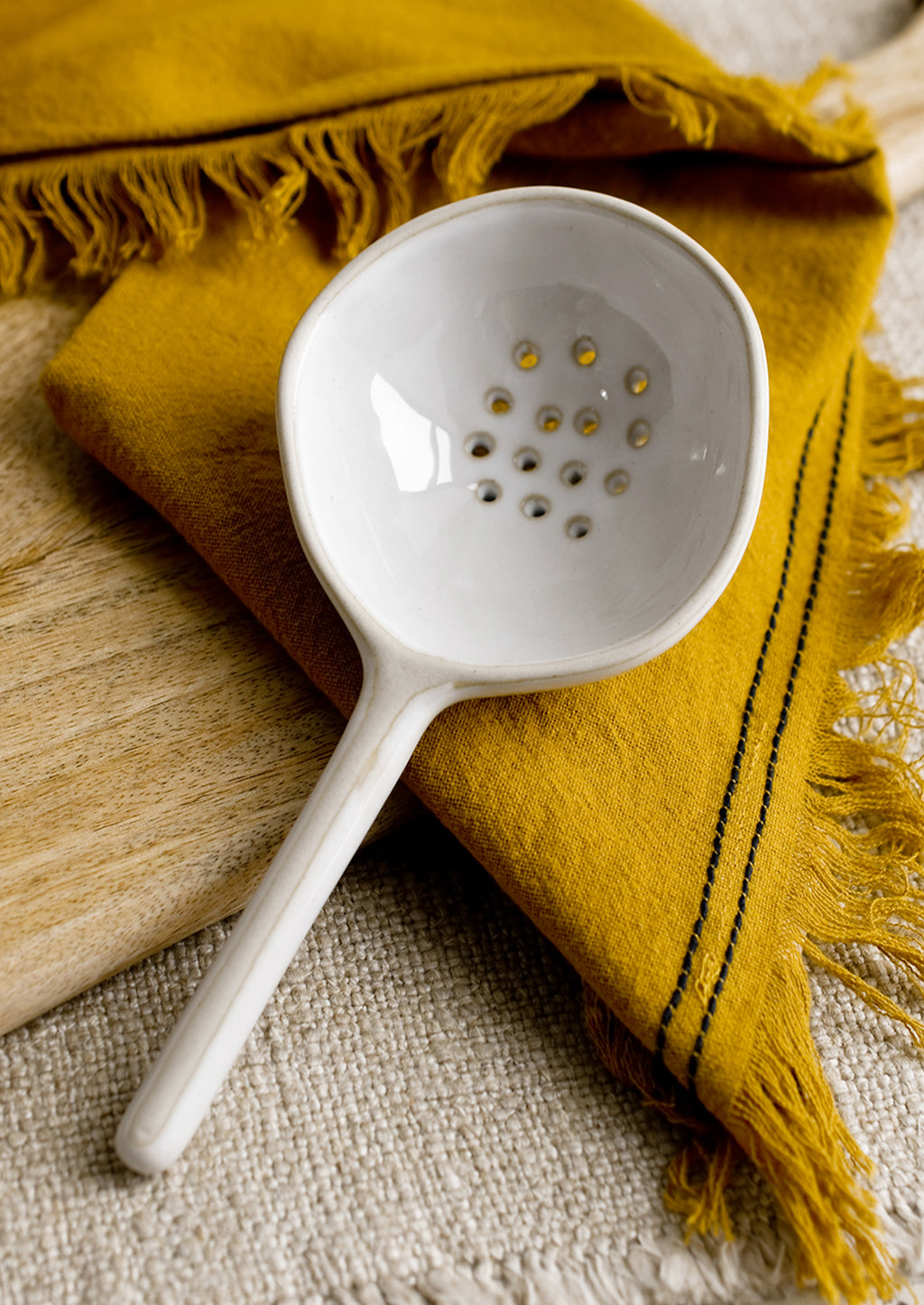 Large: A large slotted white ceramic spoon.