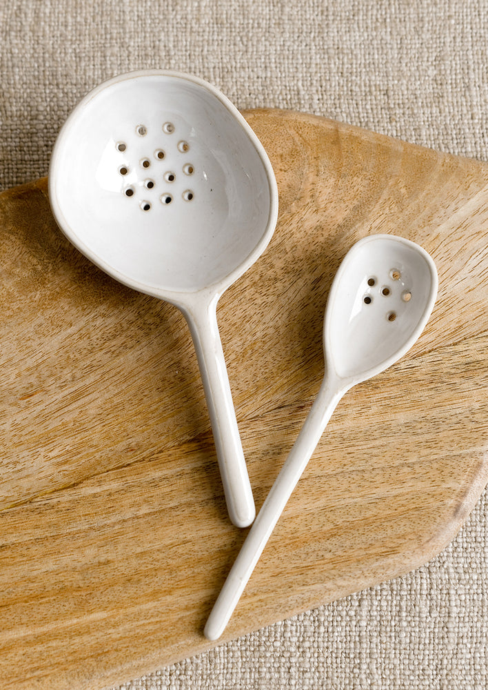 Ceramic spoons in small and large sizes in white with slotted perforation.