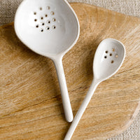 1: Ceramic spoons in small and large sizes in white with slotted perforation.